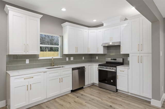 kitchen with sink, light hardwood / wood-style flooring, appliances with stainless steel finishes, white cabinets, and decorative backsplash