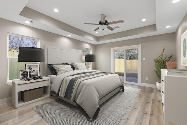 bedroom featuring a raised ceiling, access to outside, ceiling fan, and light hardwood / wood-style flooring