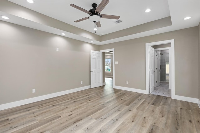 interior space featuring ceiling fan, light wood-type flooring, and a tray ceiling