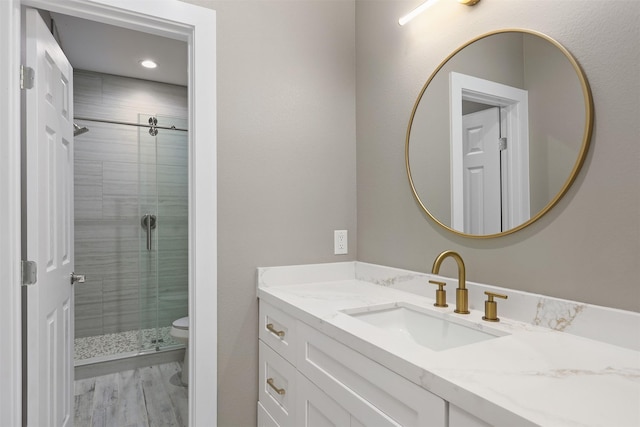 bathroom with vanity, toilet, a shower with door, and wood-type flooring