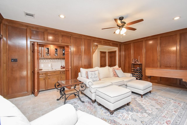 tiled living room with ceiling fan and wet bar