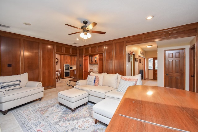 tiled living room featuring wooden walls and ceiling fan