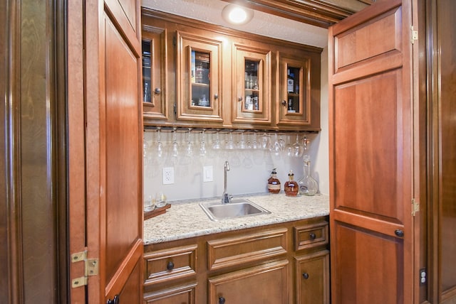 kitchen featuring light stone counters and sink