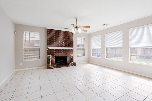 unfurnished living room featuring ceiling fan, light tile patterned flooring, a brick fireplace, and a healthy amount of sunlight