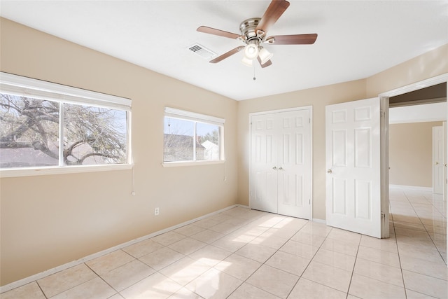 unfurnished bedroom with ceiling fan, light tile patterned floors, and a closet