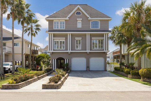 coastal home with a garage, a shingled roof, fence, and concrete driveway