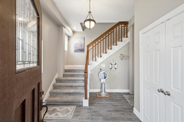 entryway with dark wood-style flooring, baseboards, and stairs