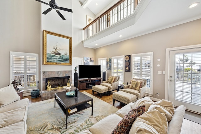 living area with crown molding, a fireplace, a towering ceiling, and wood finished floors