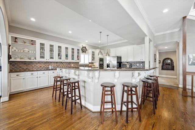 kitchen featuring stainless steel appliances, a breakfast bar, dark wood finished floors, and white cabinetry