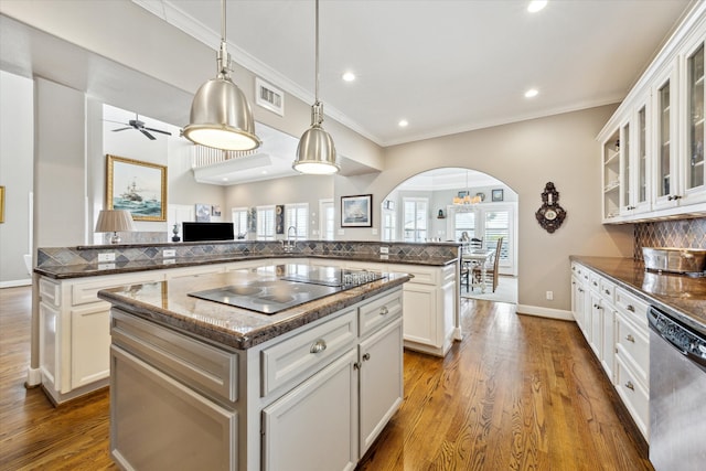 kitchen featuring arched walkways, black electric stovetop, visible vents, stainless steel dishwasher, and a center island