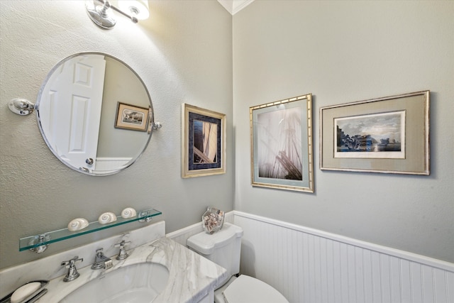 half bath featuring wainscoting, vanity, and toilet