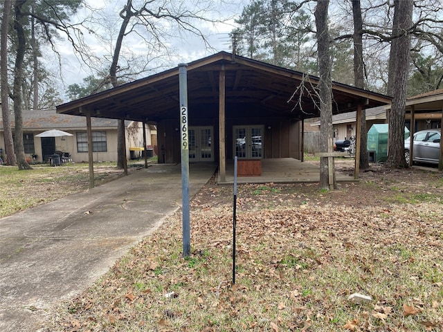 exterior space with concrete driveway, french doors, board and batten siding, and an attached carport