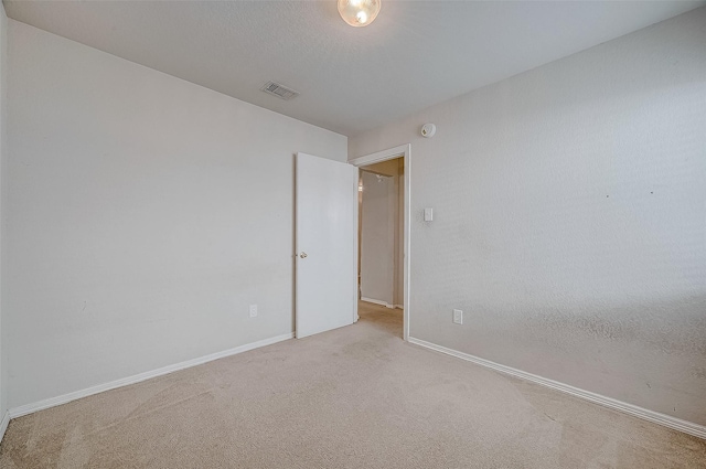 empty room with light carpet and a textured ceiling