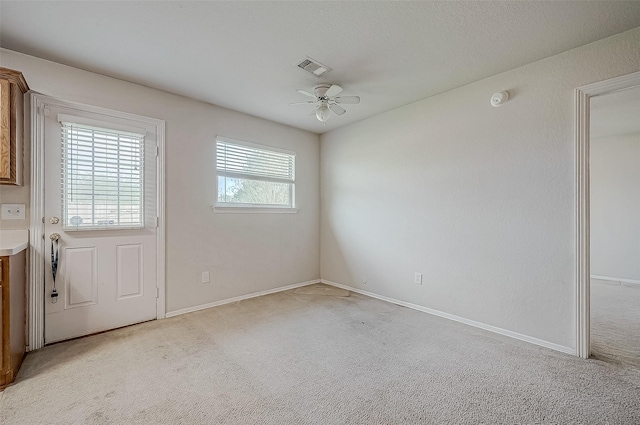 empty room featuring ceiling fan and light colored carpet