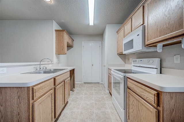 kitchen with light tile patterned flooring, sink, a textured ceiling, and white appliances