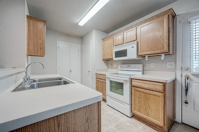 kitchen with white appliances, sink, a textured ceiling, and light tile patterned floors