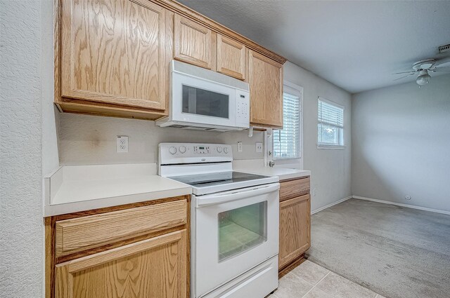 kitchen featuring ceiling fan, white appliances, light brown cabinetry, and light colored carpet