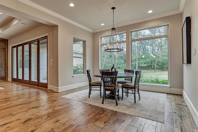 dining area featuring baseboards, a healthy amount of sunlight, crown molding, and light wood finished floors