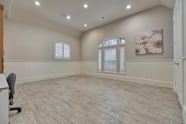 spare room with lofted ceiling, wainscoting, visible vents, and recessed lighting