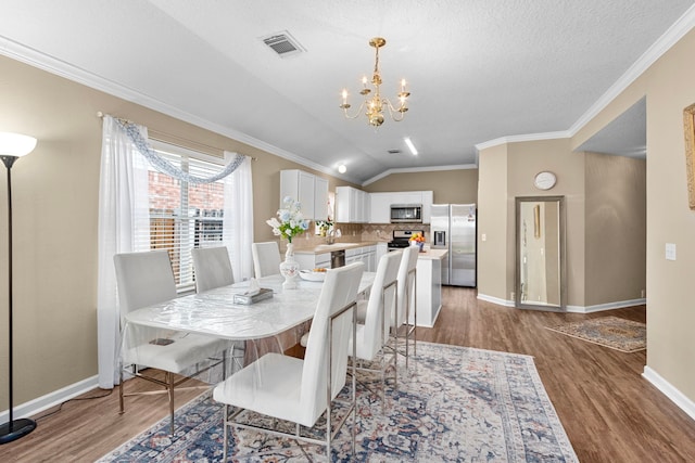 dining space with sink, crown molding, light hardwood / wood-style floors, vaulted ceiling, and a chandelier