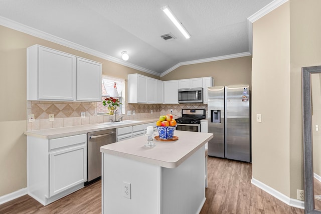 kitchen featuring a kitchen island, white cabinetry, lofted ceiling, sink, and stainless steel appliances