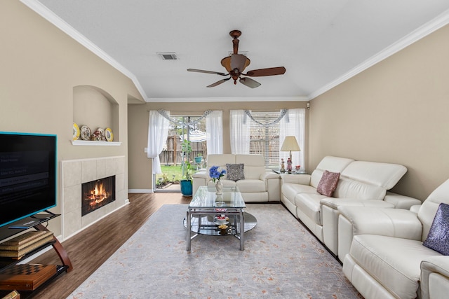 living room featuring ornamental molding, dark wood-type flooring, a fireplace, and ceiling fan