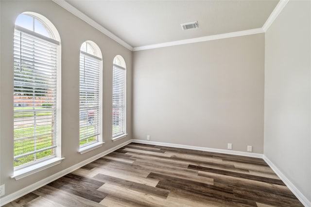 spare room with baseboards, visible vents, wood finished floors, and ornamental molding