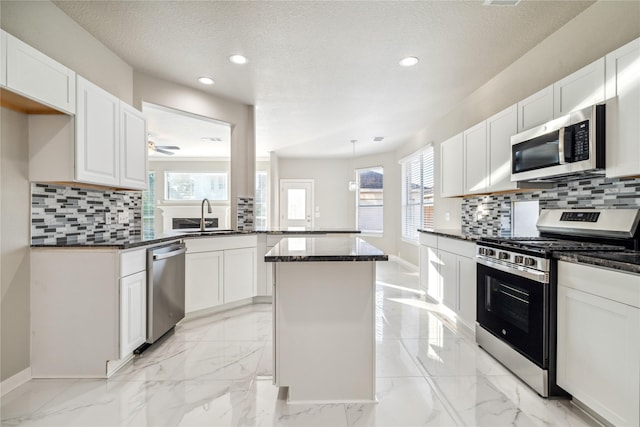 kitchen featuring marble finish floor, stainless steel appliances, a sink, and white cabinets