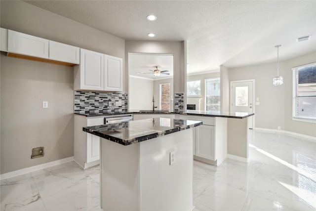 kitchen featuring dark countertops, marble finish floor, and white cabinets