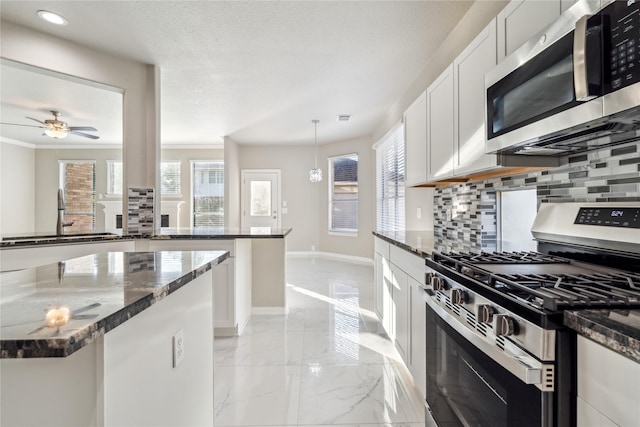 kitchen featuring white cabinets, dark stone countertops, marble finish floor, stainless steel appliances, and pendant lighting