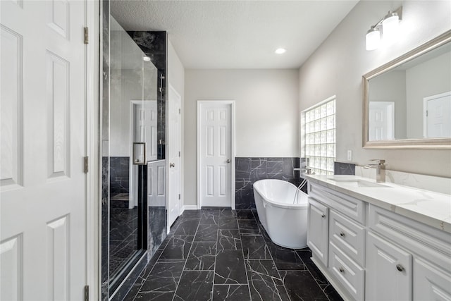 full bathroom with a stall shower, marble finish floor, a textured ceiling, vanity, and a freestanding tub