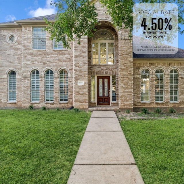 view of exterior entry featuring brick siding and a lawn