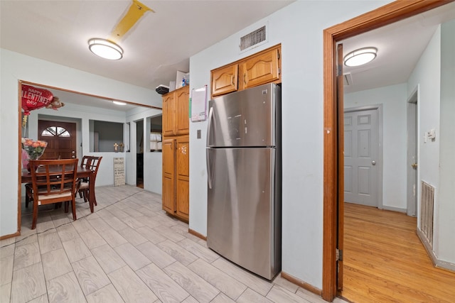 kitchen with stainless steel fridge and light hardwood / wood-style floors