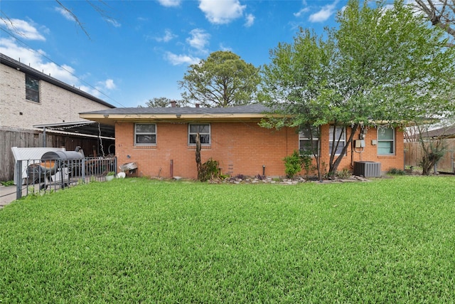 back of house with central AC unit, a yard, and a carport