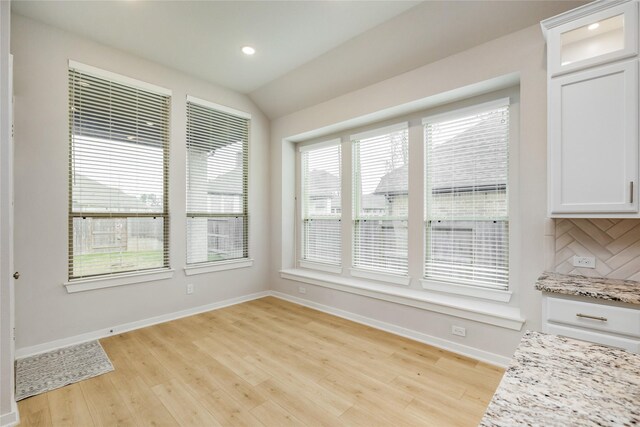 unfurnished dining area featuring lofted ceiling, recessed lighting, light wood-style flooring, and baseboards