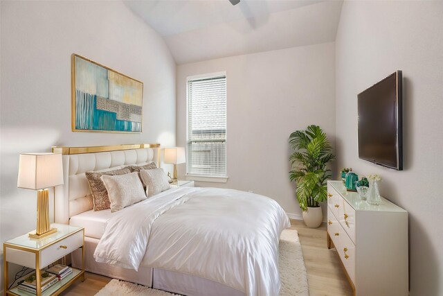 bedroom featuring baseboards, vaulted ceiling, and light wood finished floors