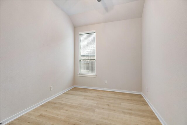 empty room with lofted ceiling, light wood finished floors, baseboards, and a ceiling fan