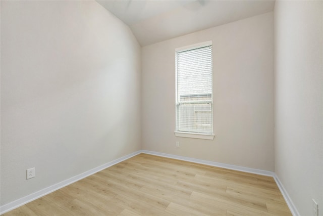 unfurnished room with vaulted ceiling, light wood finished floors, and baseboards