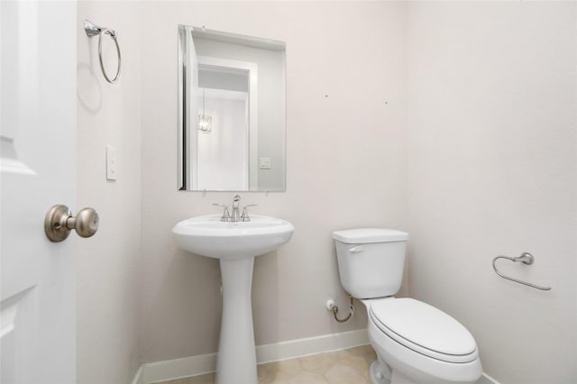 half bathroom with tile patterned flooring, toilet, and baseboards