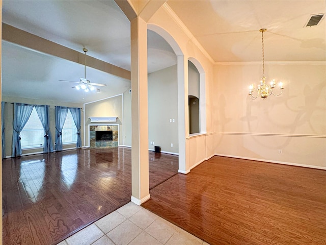 unfurnished living room with ornamental molding, light wood-type flooring, ceiling fan with notable chandelier, and a fireplace