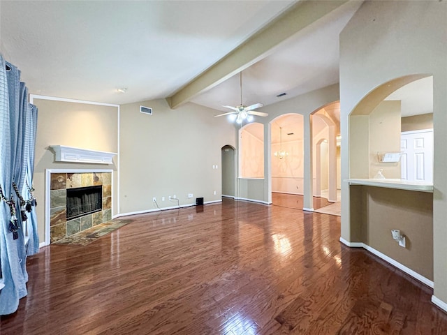 unfurnished living room featuring a tiled fireplace, dark wood-type flooring, vaulted ceiling with beams, and ceiling fan