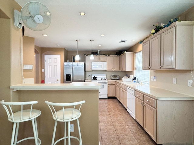 kitchen featuring sink, hanging light fixtures, light tile patterned floors, a kitchen breakfast bar, and white appliances