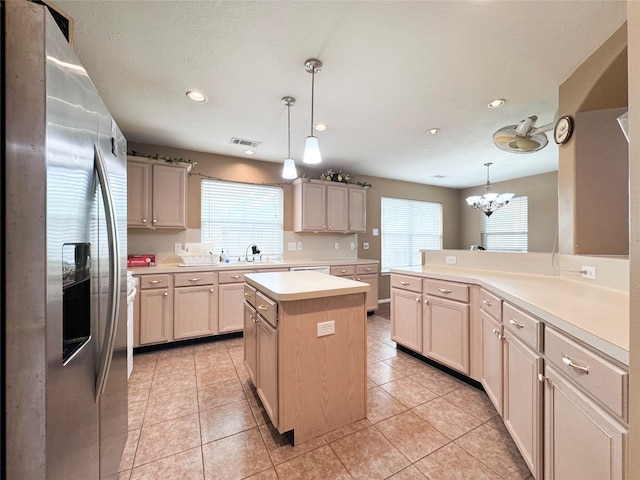 kitchen with pendant lighting, stainless steel fridge, light tile patterned flooring, and a kitchen island