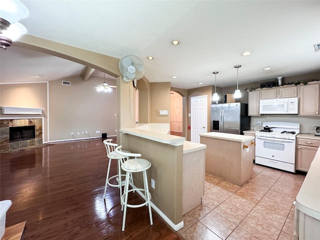 kitchen with pendant lighting, white appliances, a breakfast bar area, a center island, and lofted ceiling with beams