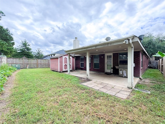 back of property featuring a storage shed, a patio area, and a lawn