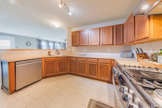 kitchen with premium range hood, sink, decorative backsplash, stainless steel appliances, and a textured ceiling