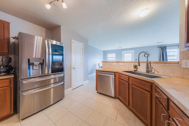 kitchen with stainless steel appliances, tasteful backsplash, sink, and light tile patterned flooring