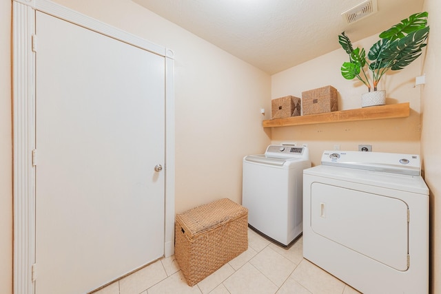 washroom with light tile patterned flooring, a textured ceiling, and washer and clothes dryer