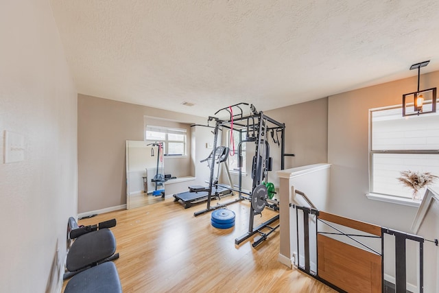 workout room with a textured ceiling and light wood-type flooring