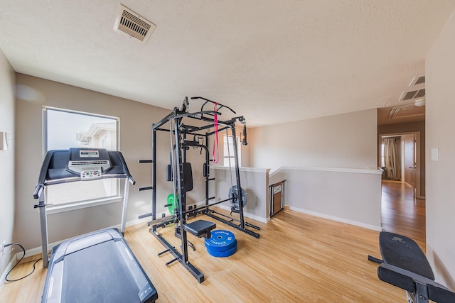 exercise room with hardwood / wood-style flooring and a textured ceiling